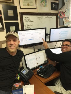 Two team members at their desks, one pointing at a monitor